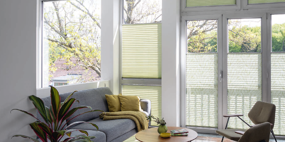 Salon lumineux avec fenêtres habillées de stores plissés colorés