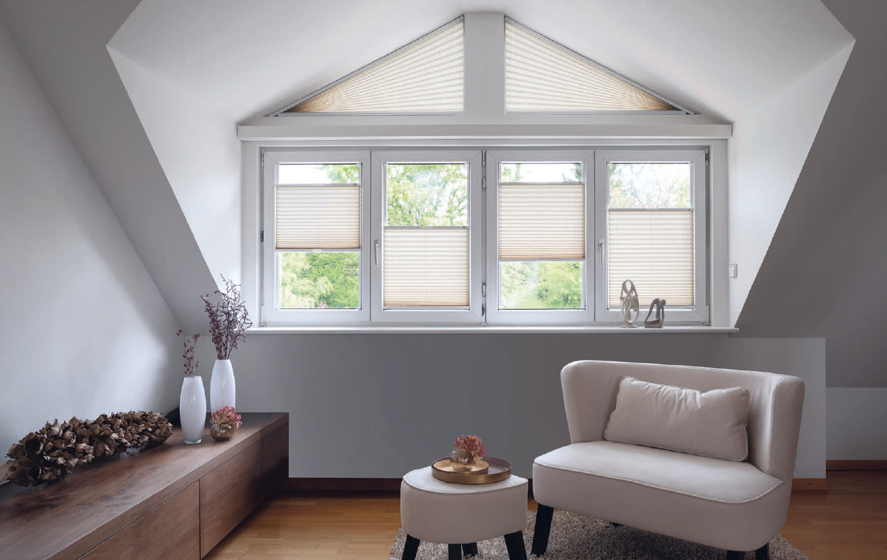 Espace sous les combles avec stores plissés colorés modulant la lumière